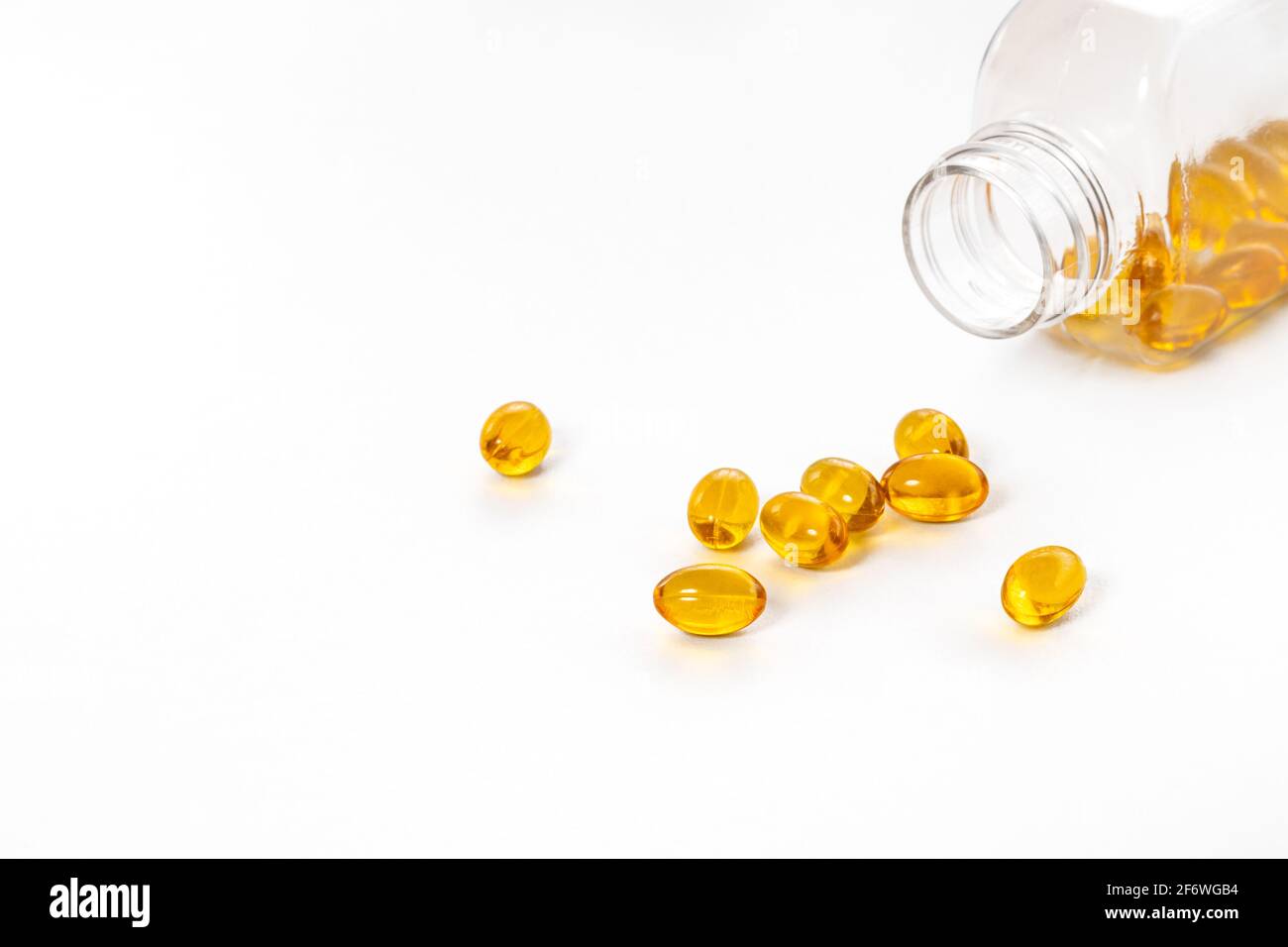 Capsules d'huile de poisson de couleur jaune avec flacon en verre sur fond blanc. Banque D'Images