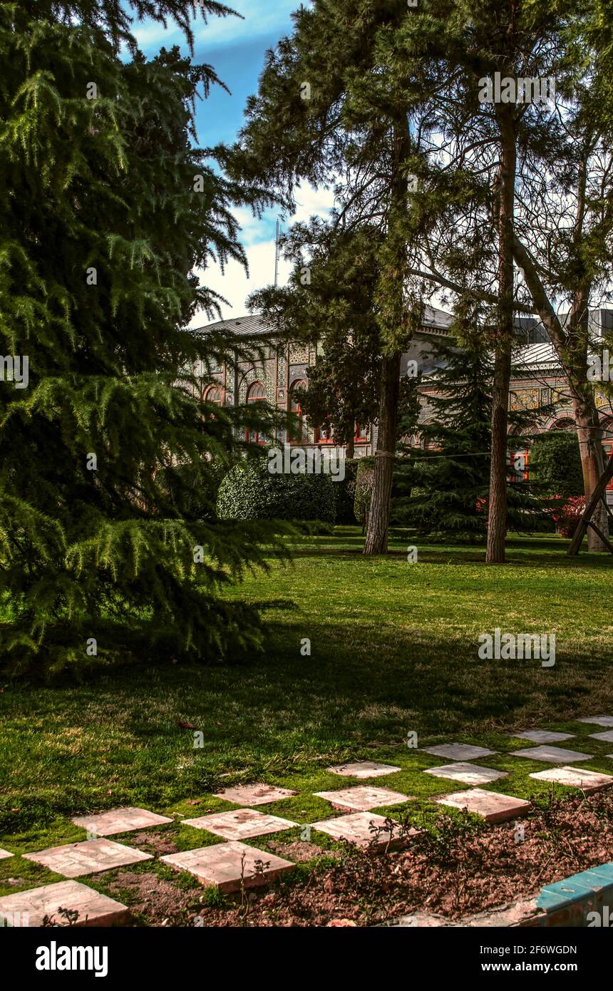 Une belle pelouse recouverte d'herbe verte et d'un damier chemin avec de grands conifères contre le ciel bleu d'hiver dedans L'ancien jardin du Golestan Banque D'Images