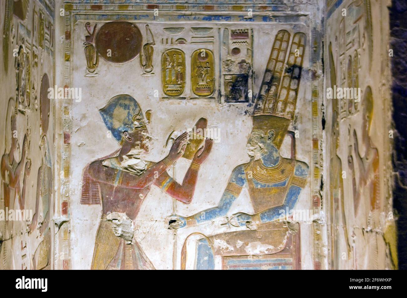 Une ancienne sculpture hiéroglyphique égyptienne du Pharoah Seti présentant un don au dieu Amun. Niche sculptée et peinte au Temple d'Abydos, Egyp Banque D'Images