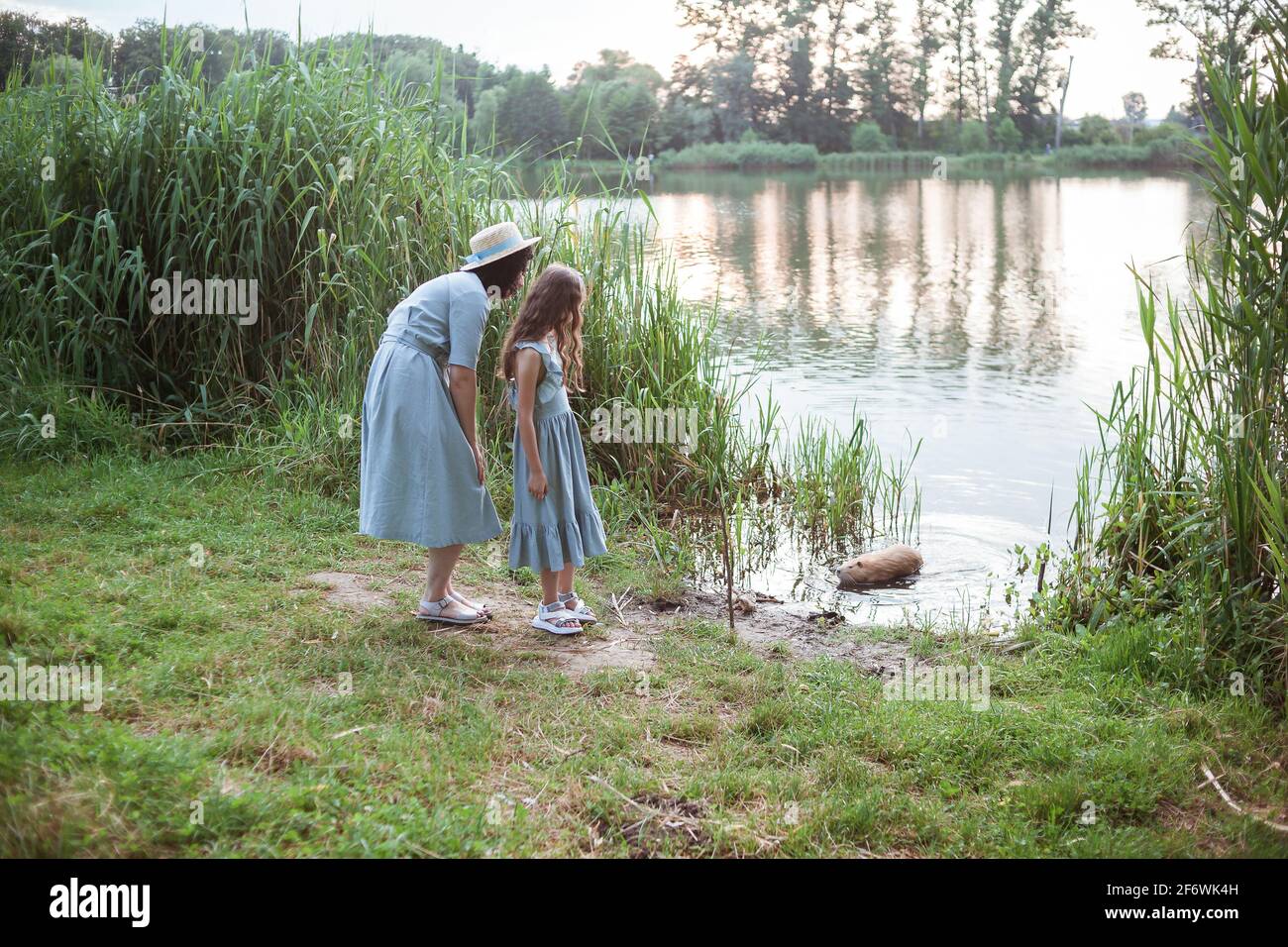 Une fille se tient sur la rive du lac et regarde la nutrition dans l'eau Banque D'Images