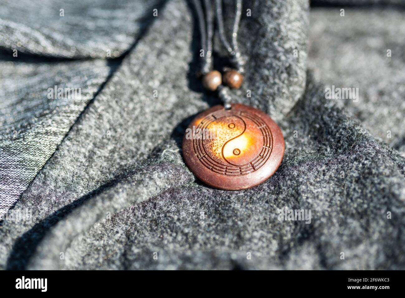 Yin Yang pendentif collier brun couleur tirer à la main dehors dans une journée ensoleillée de gros plan. Mise au point sélective Banque D'Images
