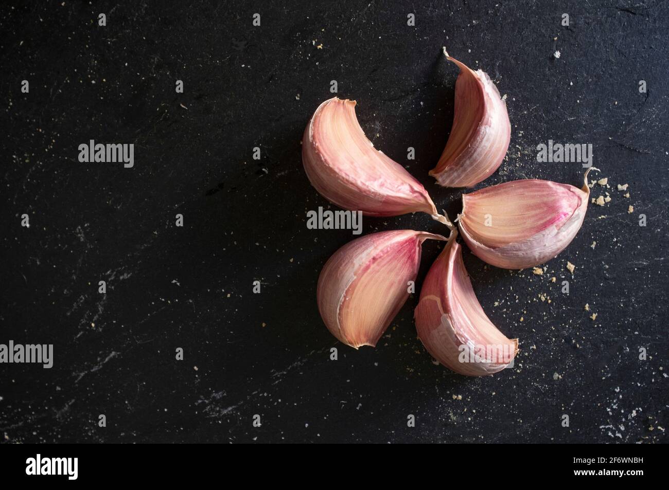 Gousses d'ail rose espagnol. Isolé sur ardoise noire avec couvert de crumbles à pain Banque D'Images