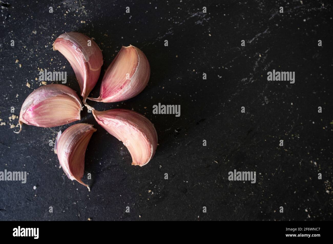 Gousses d'ail rose espagnol. Isolé sur ardoise noire avec couvert de crumbles à pain Banque D'Images