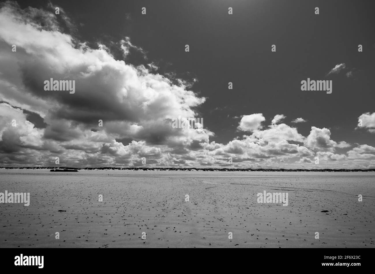 Sable, ciel, nuages sur la plage à marée basse près de Brancaster / RSPB Titchwell Marsh, Norfolk, Royaume-Uni. NOIR ET BLANC Banque D'Images