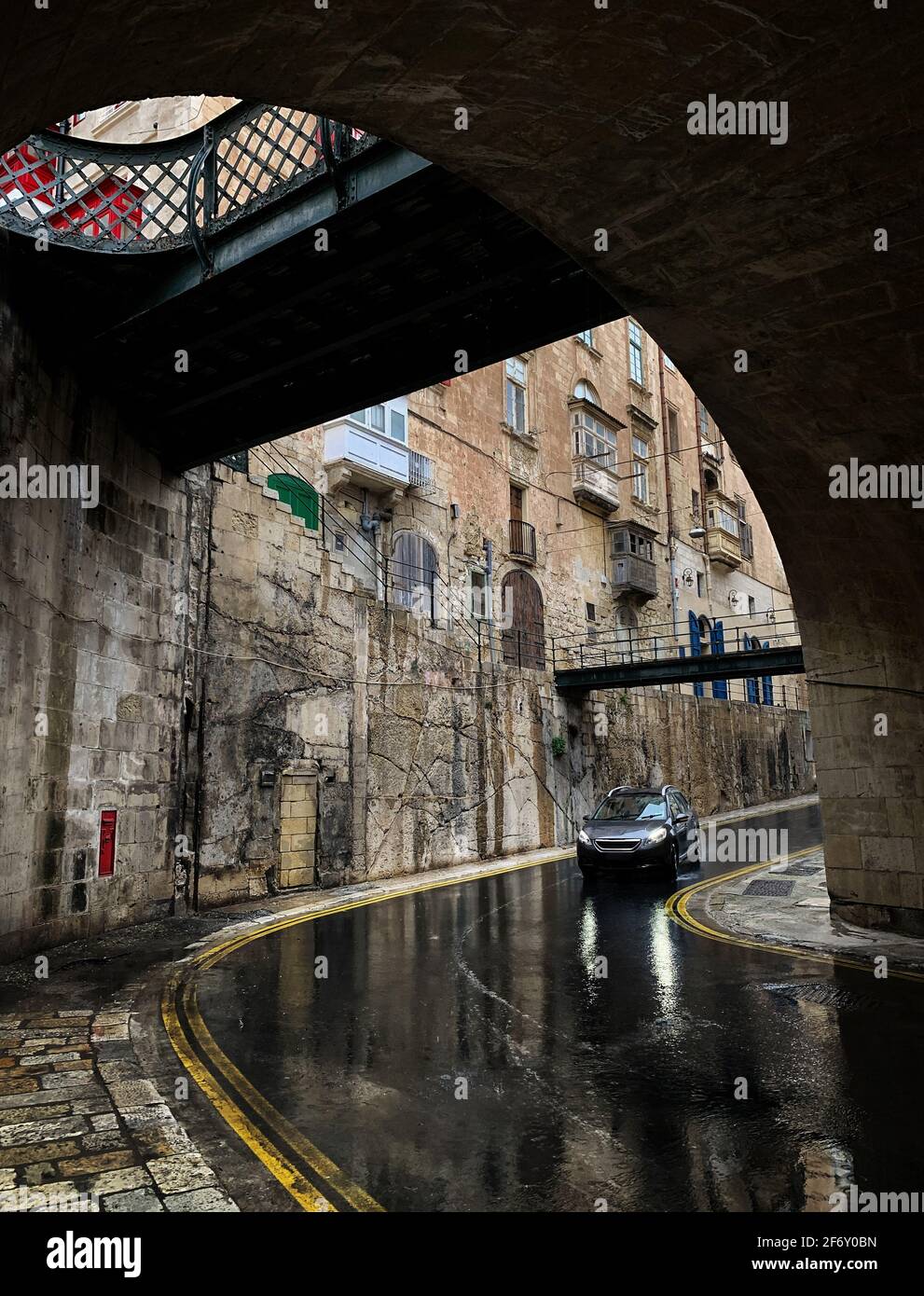 Voiture en voiture à travers la ville sous la pluie, la Valette, Malte Banque D'Images