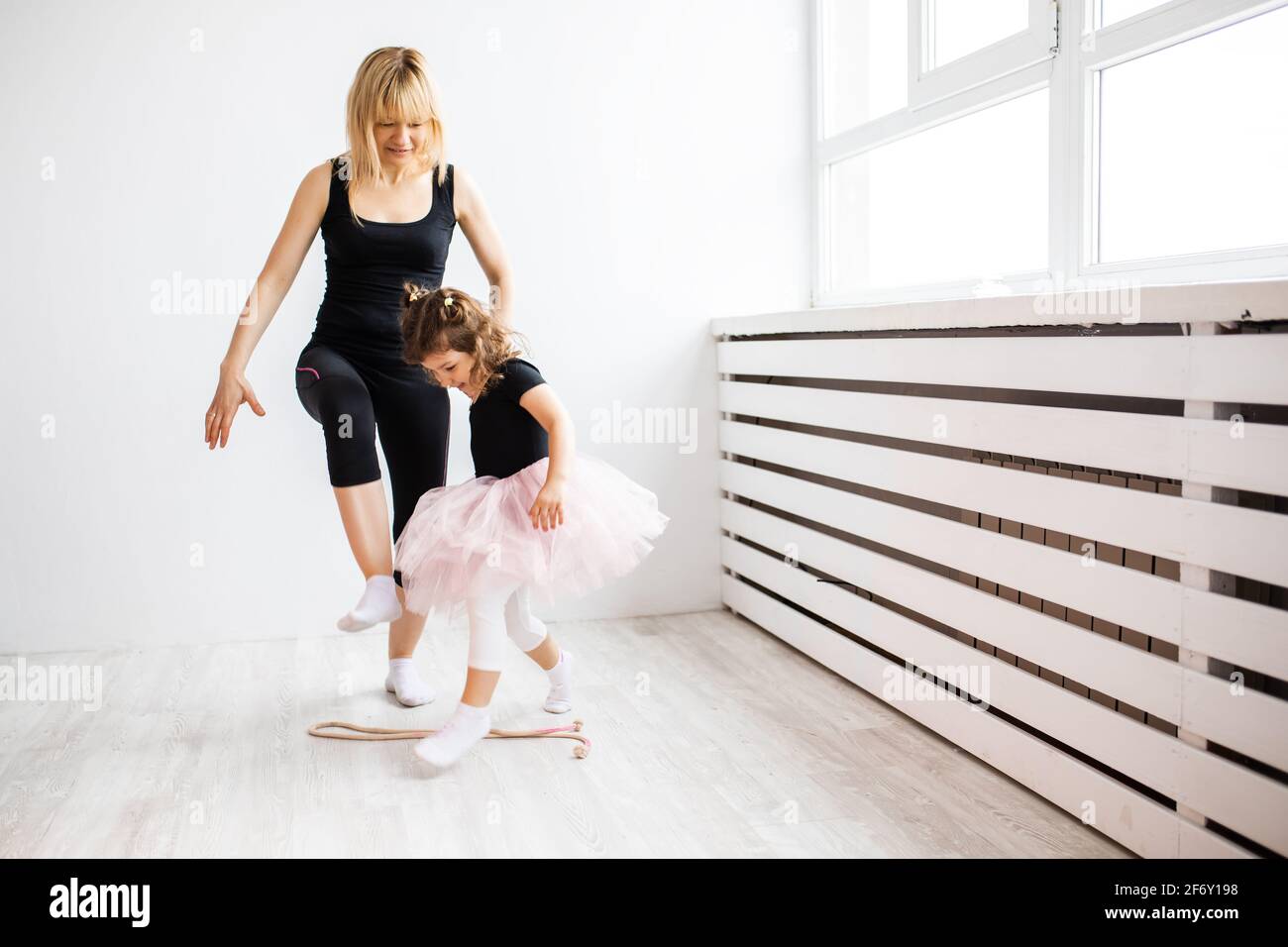 Femme maman se livre à danser avec sa petite fille, est engagée dans la gymnastique dans un intérieur blanc, photo de style de vie Banque D'Images