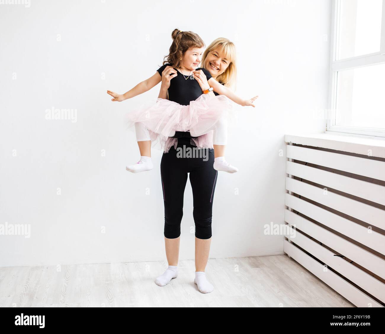 Femme maman se livre à danser avec sa petite fille, est engagée dans la gymnastique en intérieur blanc, photo de style de vie à la maison Banque D'Images