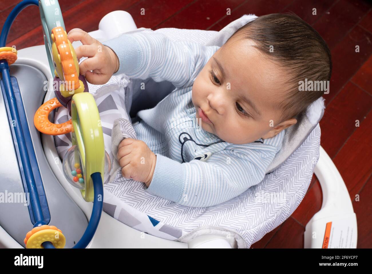 bébé garçon de 4 mois assis dans un siège pour bébé intéressé par le bar à  jouets, atteignant pour toucher le jouet Photo Stock - Alamy