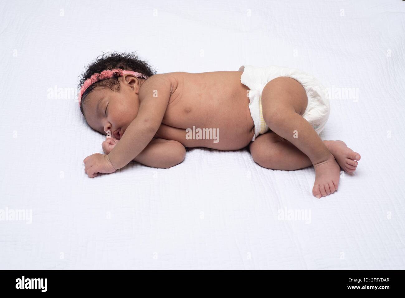 Nouveau-né bébé fille de 3 semaines, dormir sur le côté, pleine longueur Banque D'Images