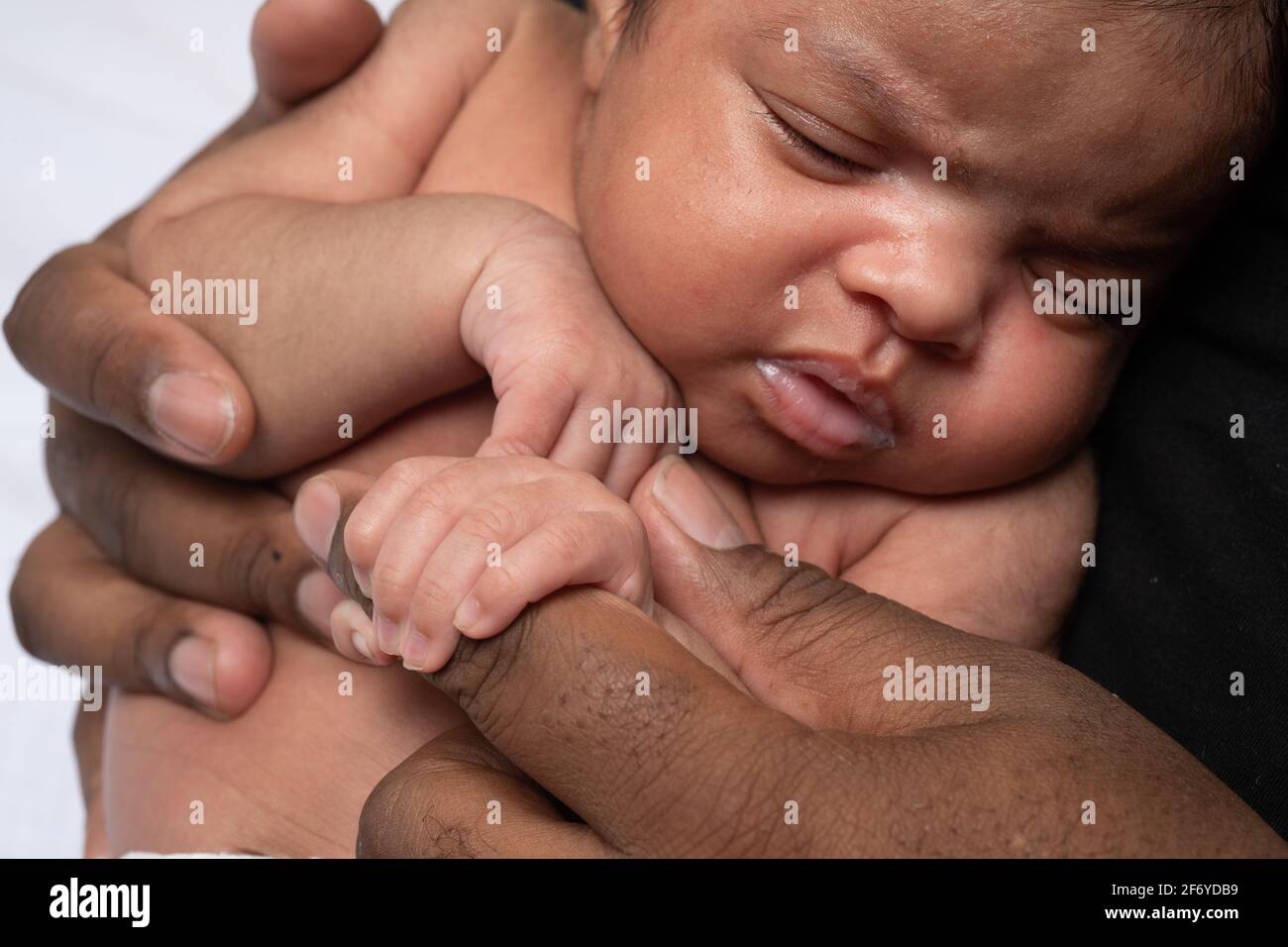 Nouveau-né bébé fille de 3 semaines saisissant le doigt du père Banque D'Images