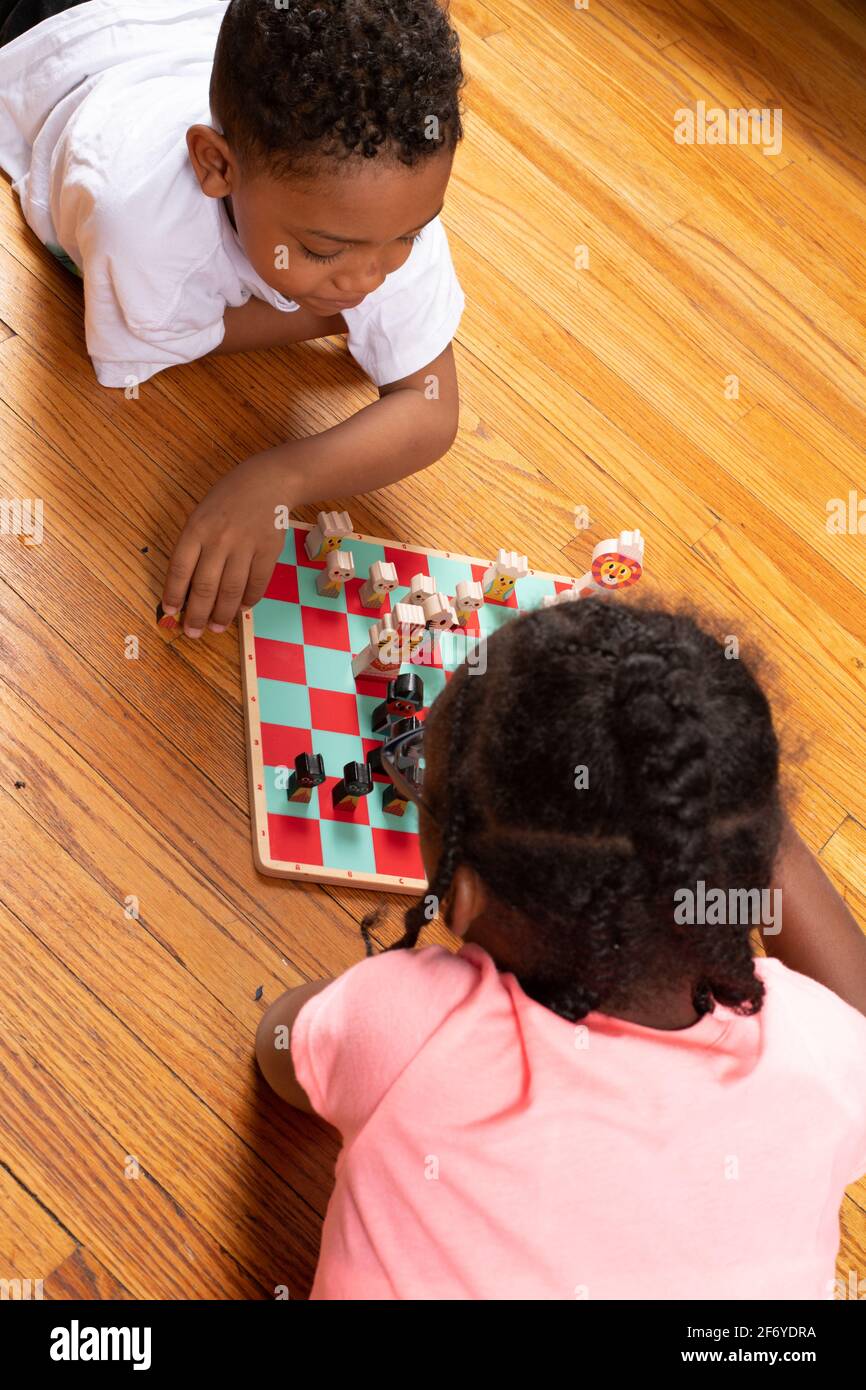 fille de 11 ans jouant aux échecs avec son frère de 6 ans, jouant au jeu et lui enseignant comment jouer Banque D'Images