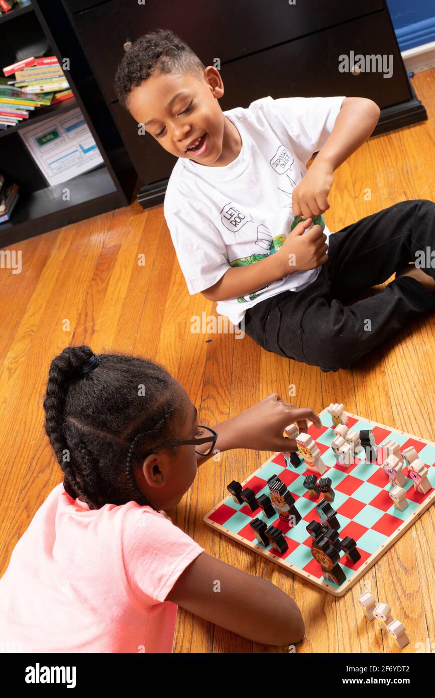 fille de 11 ans jouant aux échecs avec son frère de 6 ans, jouant au jeu et lui enseignant comment jouer Banque D'Images