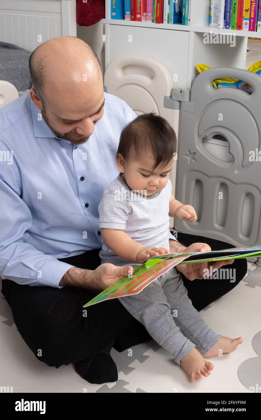 bébé garçon de 8 mois, avec père, lire à, bébé touchant la page de livre Banque D'Images