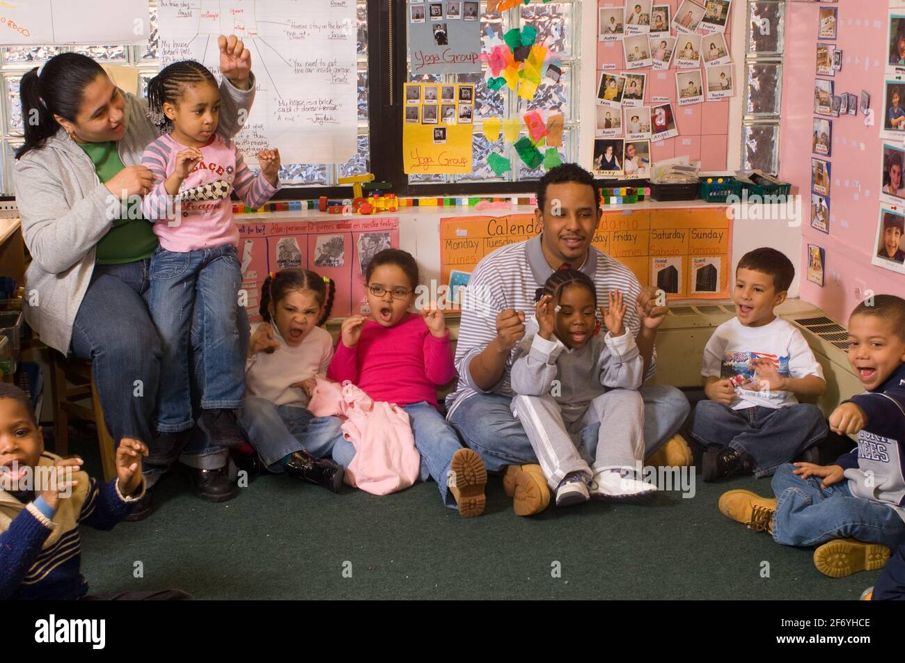 Classe préscolaire, 4 ans, enseignante et étudiante de sexe masculin professeur avec le groupe au temps de cicrle chantant la chanson avec la main gestes Banque D'Images