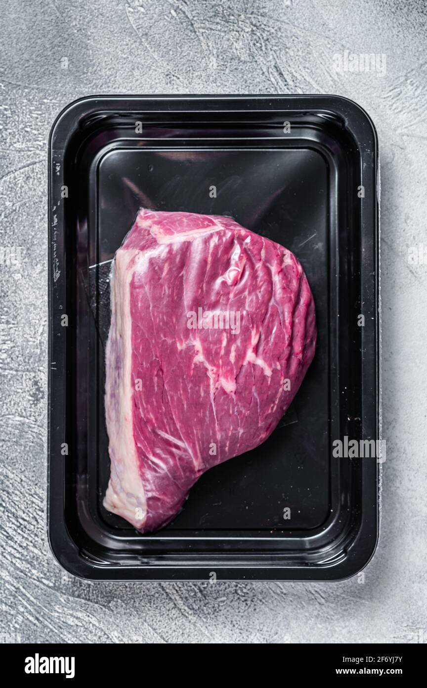 Steak de bœuf cru ou steak de viande de bœuf au sirloin dans un emballage sous vide. Arrière-plan blanc. Vue de dessus Banque D'Images