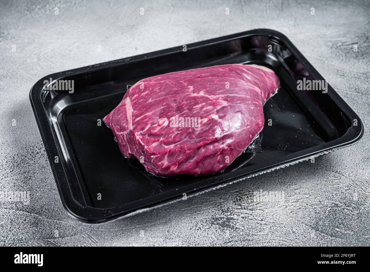Steak de bœuf cru ou steak de viande de bœuf au sirloin dans un emballage sous vide. Arrière-plan blanc. Vue de dessus Banque D'Images
