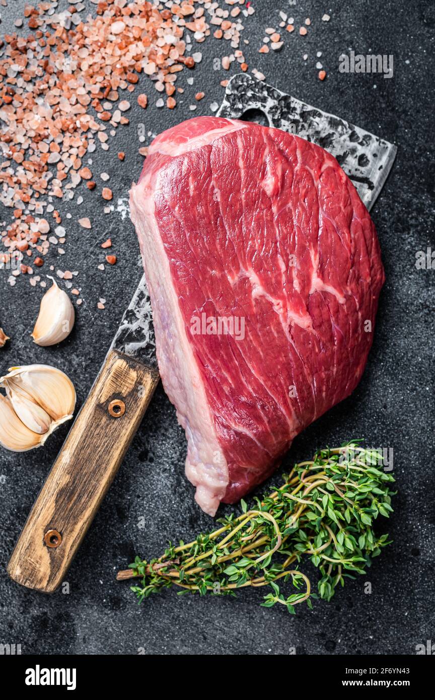 Bœuf cru frais coupé ou steak de chapeau de sirloin sur le couperet de boucher. Arrière-plan noir. Vue de dessus Banque D'Images