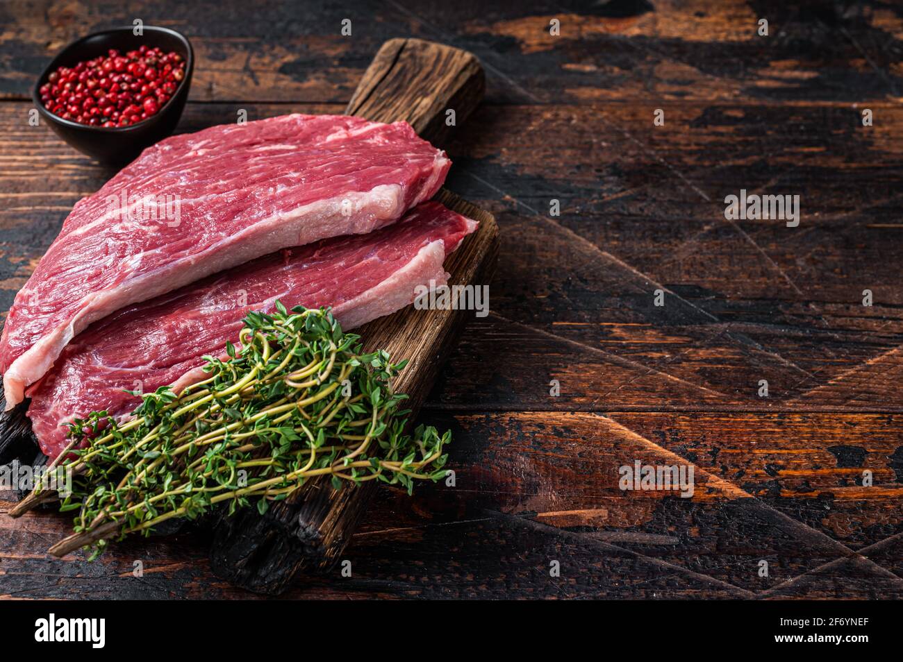 Steak de chapeau de sirloin cru ou steak de Picanha sur une planche de bois au thym. Arrière-plan en bois sombre. Vue de dessus. Copier l'espace Banque D'Images