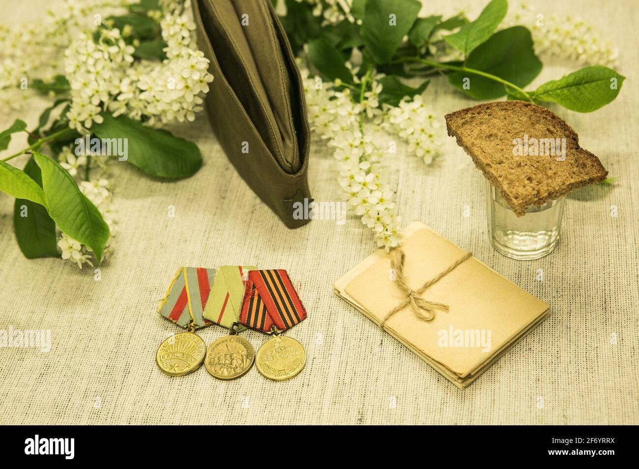 Jour de la victoire. Nous nous souvenons des exploits de nos grands-pères. Ruban de St. George, médailles, lettres militaires sur fond de cerisier d'oiseau et de chapeau. Banque D'Images