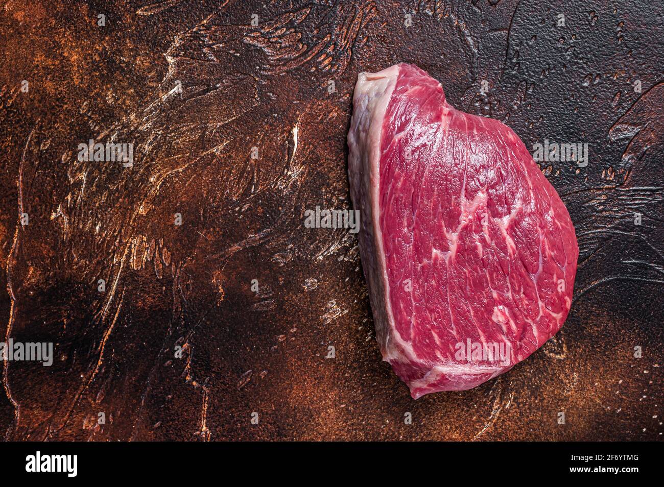 Bœuf cru coupé ou steak de viande de sirloin sur la table de boucher. Arrière-plan sombre. Vue de dessus. Copier l'espace Banque D'Images