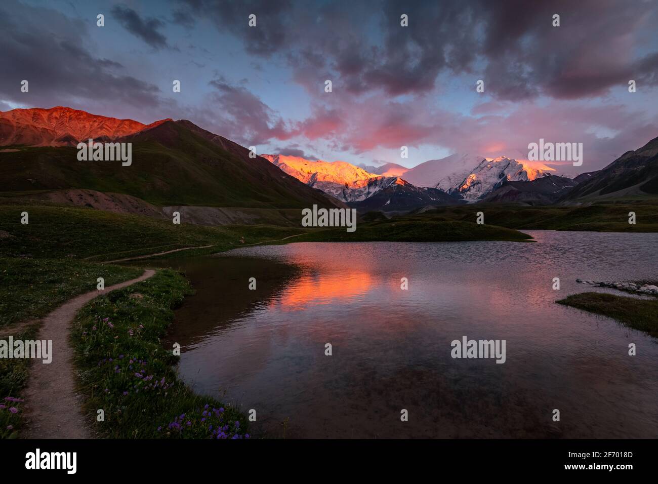Coucher de soleil rouge-violet idyllique sur le lac du glacier avec des reflets de montagnes enneigées dans le camp de base de Lénine Peak, les montagnes de Pamir, Kirghizistan Banque D'Images