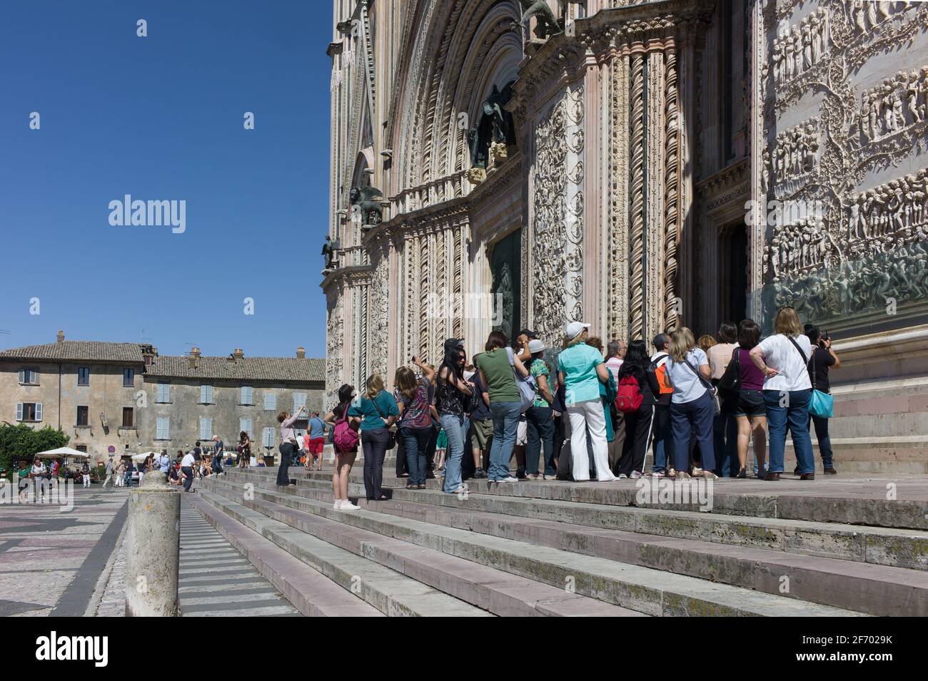 Les touristes se tiennent sur les marches en face de la cathédrale, obtenir une explication du relief sur les murs et entrer dans la cathédrale Duomo d'Orvieto Banque D'Images