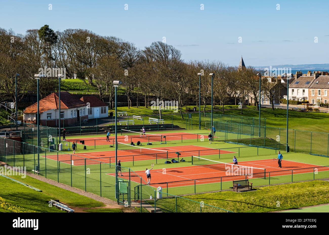 Personnes jouant au tennis sur les courts publics dans le parc au soleil, North Berwick, East Lothian, Écosse, Royaume-Uni Banque D'Images