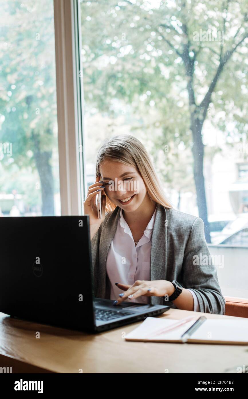 Assistant virtuel, entrepreneur indépendant, services administratifs aux clients, en fonctionnement à l'extérieur, bureau à domicile. Jeune femme parlant au téléphone et Banque D'Images