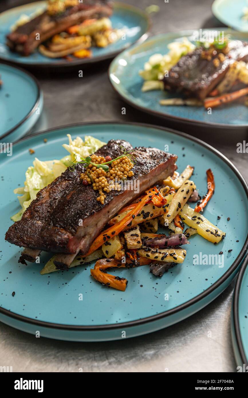 Côtelettes de rechange dans un comptoir de restaurant servi avec des racines grillées légumes Banque D'Images
