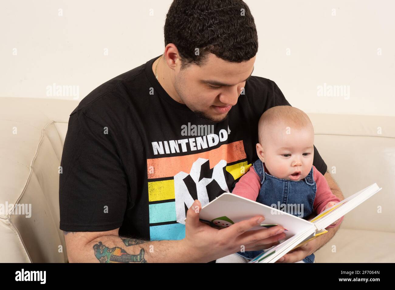 Livre de lecture de père avec bébé fille de 4 mois qui est intéressé et engagé Banque D'Images