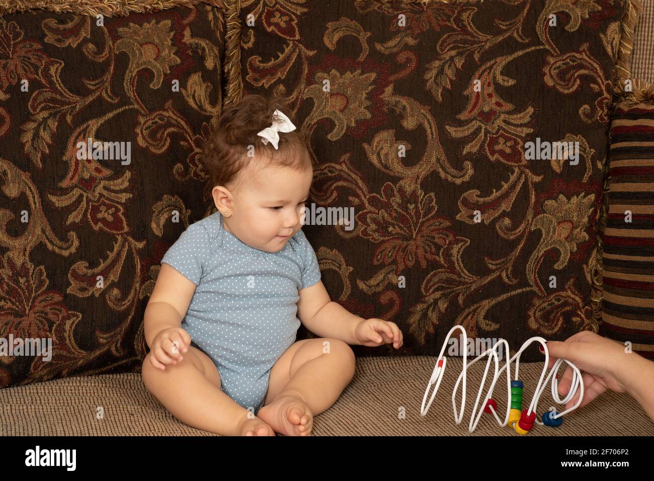 Bebe Fille De 7 Mois Assis Sur Le Canape Interesse Perle De Fil Jouet Piaget Objet Permanence Serie 1 De 2 Photo Stock Alamy