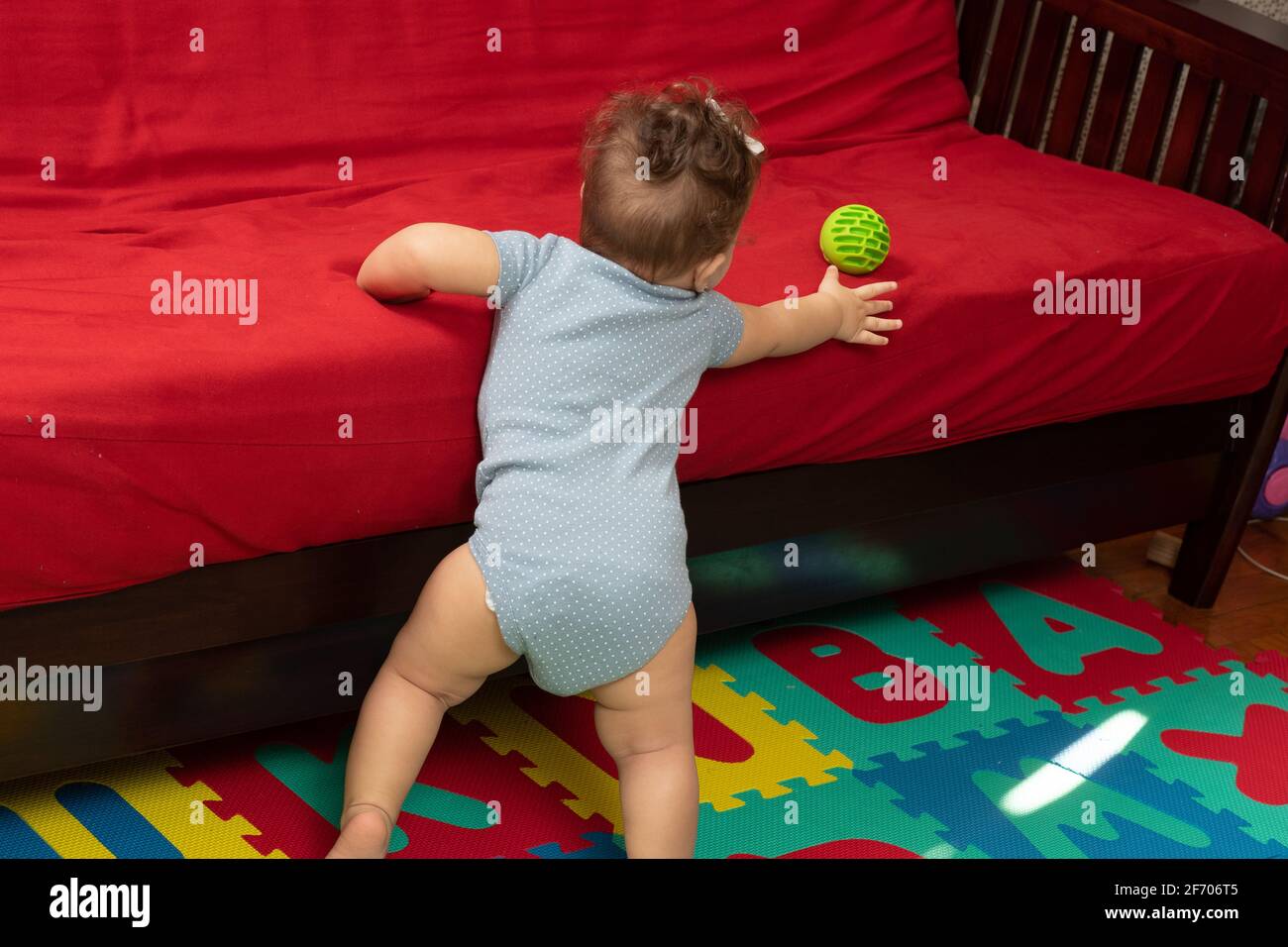 Bebe Fille De 7 Mois Debout Avec Un Support Au Canape Se Deplacant Et Atteignant Pour Le Ballon Marchant Avec Un Support Photo Stock Alamy