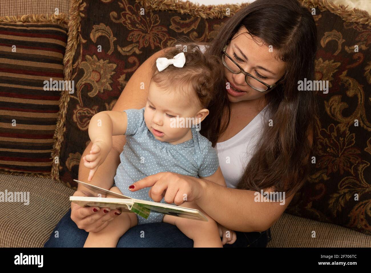 bébé fille de 7 mois lu par la mère, bby pointant vers le livre Banque D'Images