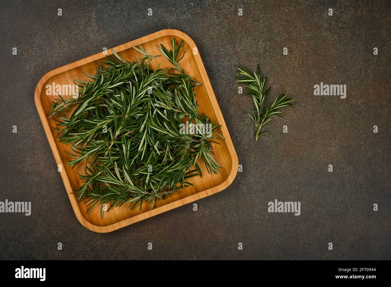 Gros plan sur les feuilles de romarin vert frais sur une assiette en bois de bambou sur la table, vue en hauteur, juste au-dessus Banque D'Images