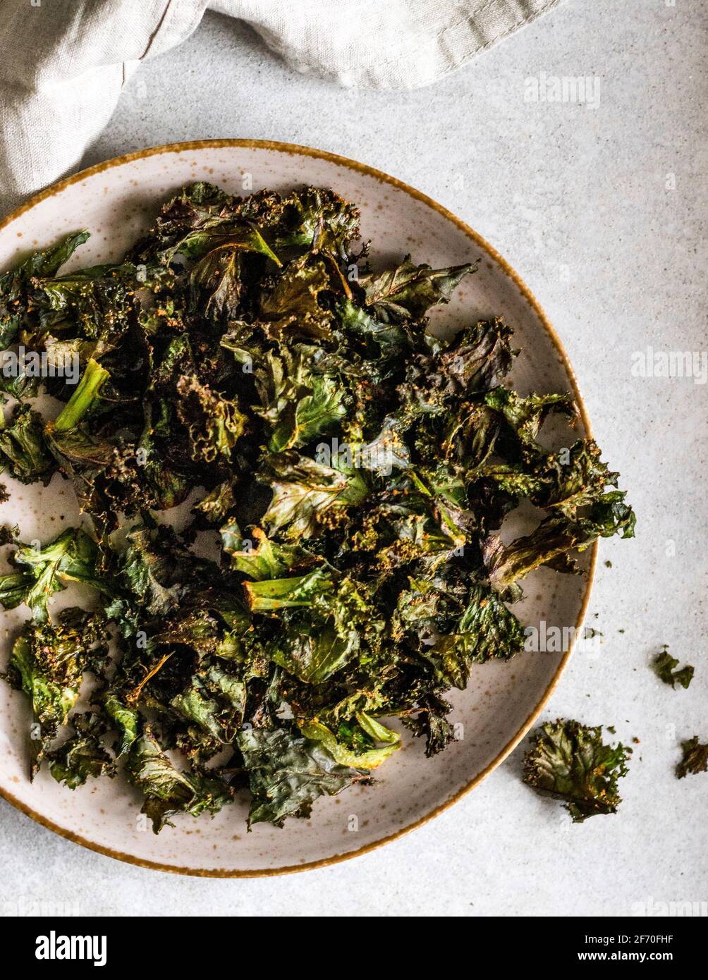 Assiette posée sur un comptoir de cuisine avec des chips de chou croustillantes fraîchement préparées avec un peu de sel et de piment. Banque D'Images