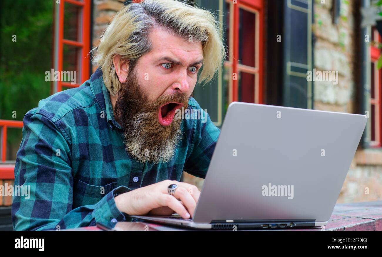 Jeux en ligne. Gagner en ligne. Travail en ligne. Homme barbu plein d'enthousiasme avec un ordinateur portable à l'extérieur. Freelance Banque D'Images