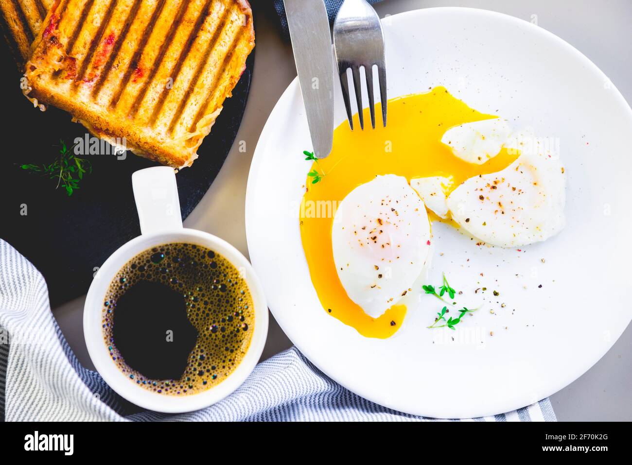 Œufs pochés le matin avec un sandwich rôti et une tasse de café Banque D'Images