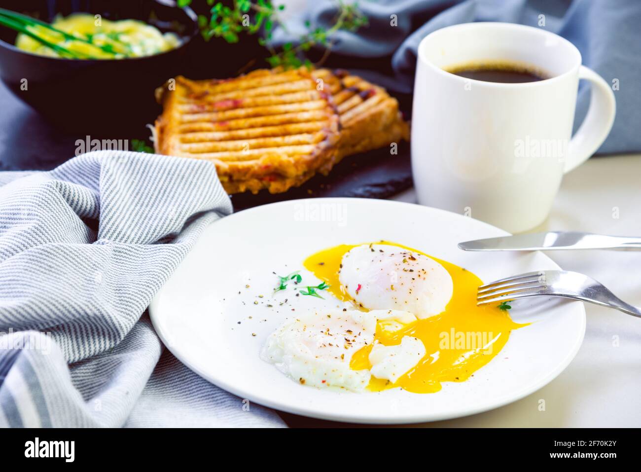 Œufs pochés le matin avec un sandwich rôti et une tasse de café Banque D'Images