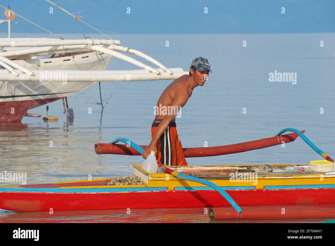 Le pêcheur philippin se prépare à prendre son canot en saillie pour pêcher dans la mer de Visayan au large de Moalboal, île de Cebu, Philippines. Banque D'Images