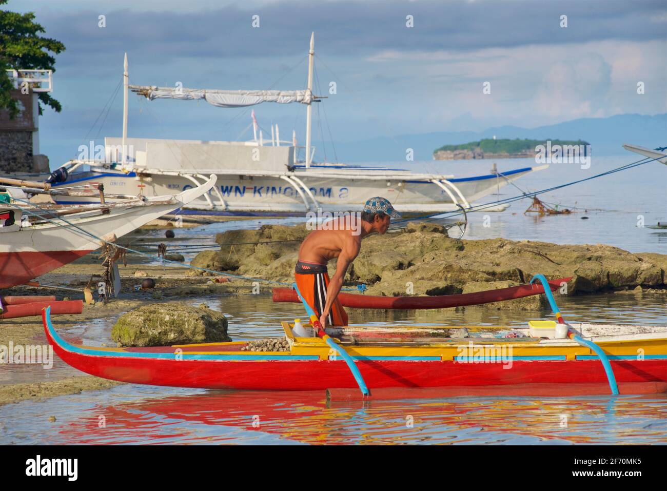 Le pêcheur philippin se prépare à prendre son canot en saillie pour pêcher dans la mer de Visayan au large de Moalboal, île de Cebu, Philippines. Banque D'Images