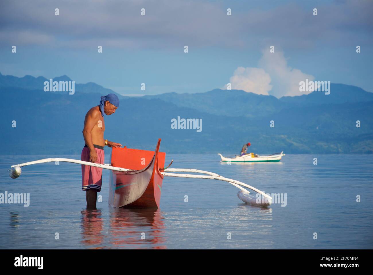 Le pêcheur philippin se prépare à prendre son canot en saillie pour pêcher dans la mer de Visayan au large de Moalboal, île de Cebu, Philippines. Banque D'Images