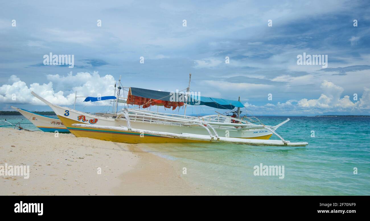 Canoës-outrigger sur une plage de sable. Utilisé pour transporter des visiteurs de Bantayan à Sillon (également connu sous le nom de « l'île vierge »), Cebu Phippines Banque D'Images