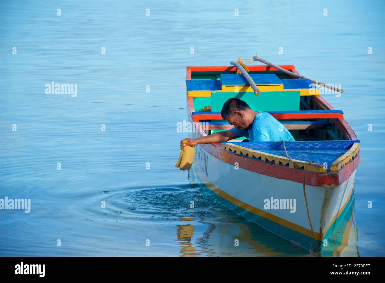 Village logon, île Malapascua. Un philippin local essorant de l'eau de son ig son bateau. Mer de Visayan, Cebu, Philippines. Banque D'Images