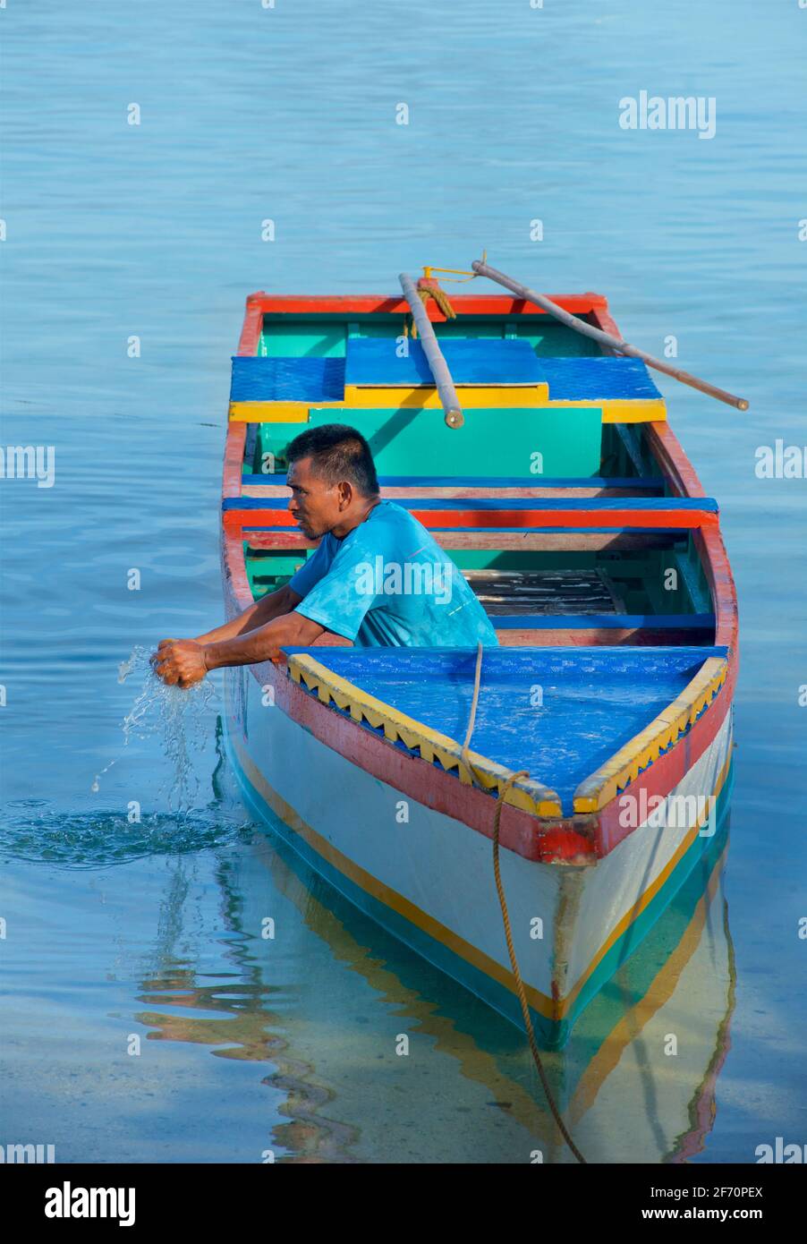 Village logon, île Malapascua. Un philippin local essorant de l'eau de son ig son bateau. Mer de Visayan, Cebu, Philippines. Banque D'Images
