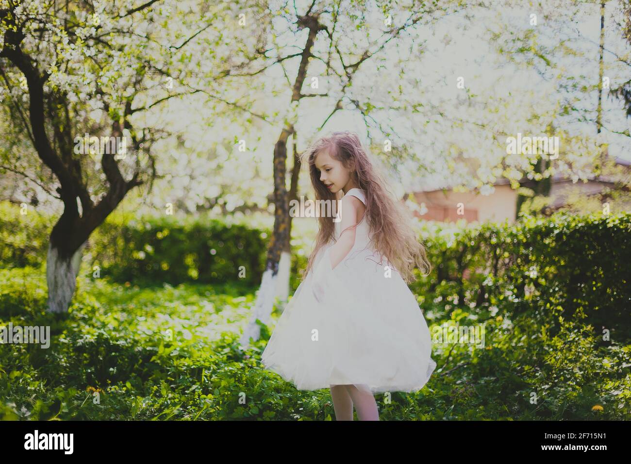 Petite fille en veste noire et robe blanche dansant à l'intérieur le jardin  de la cerise de printemps Photo Stock - Alamy