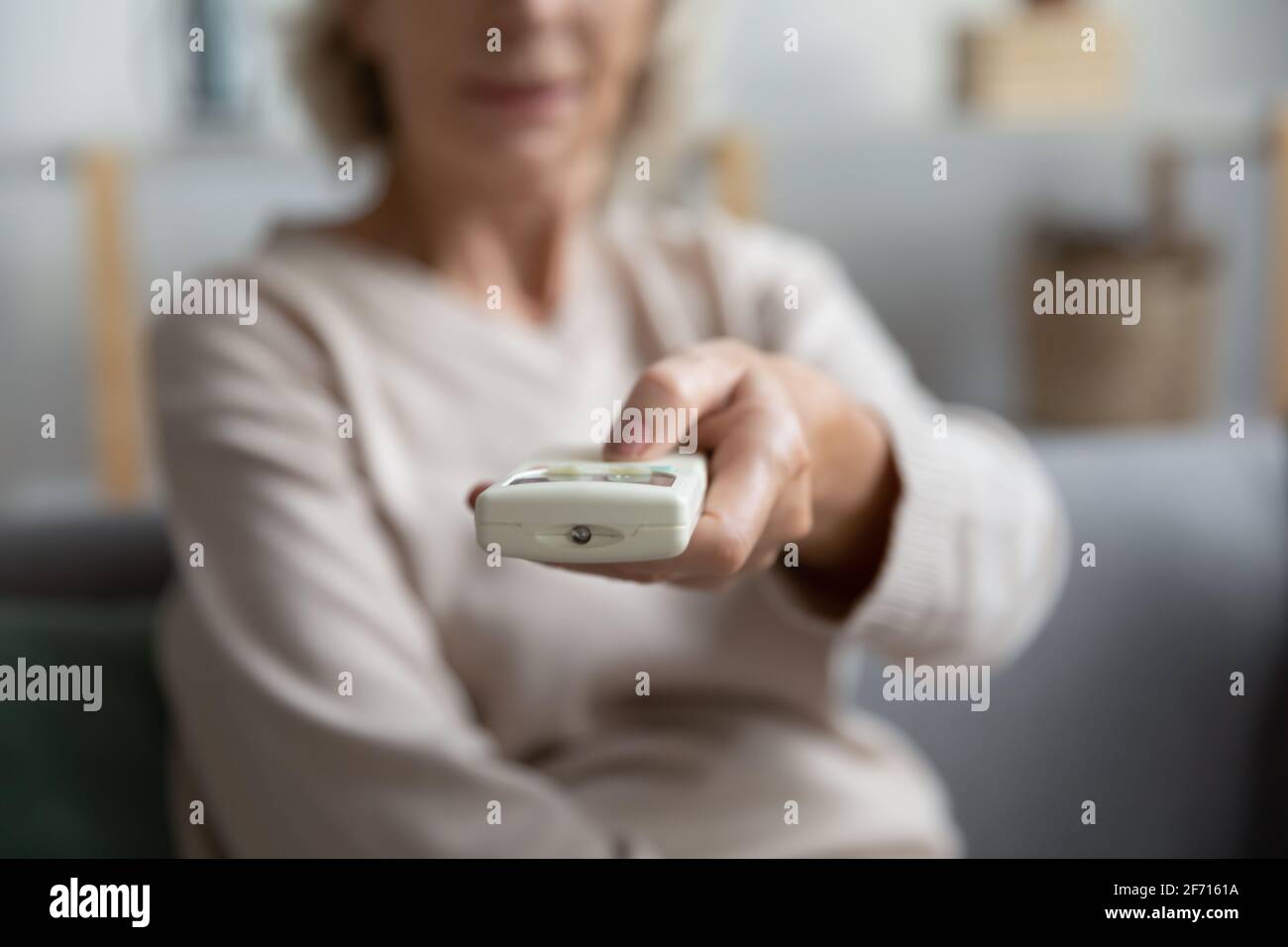 Main d'une femme d'âge mûr qui commande la télécommande Banque D'Images