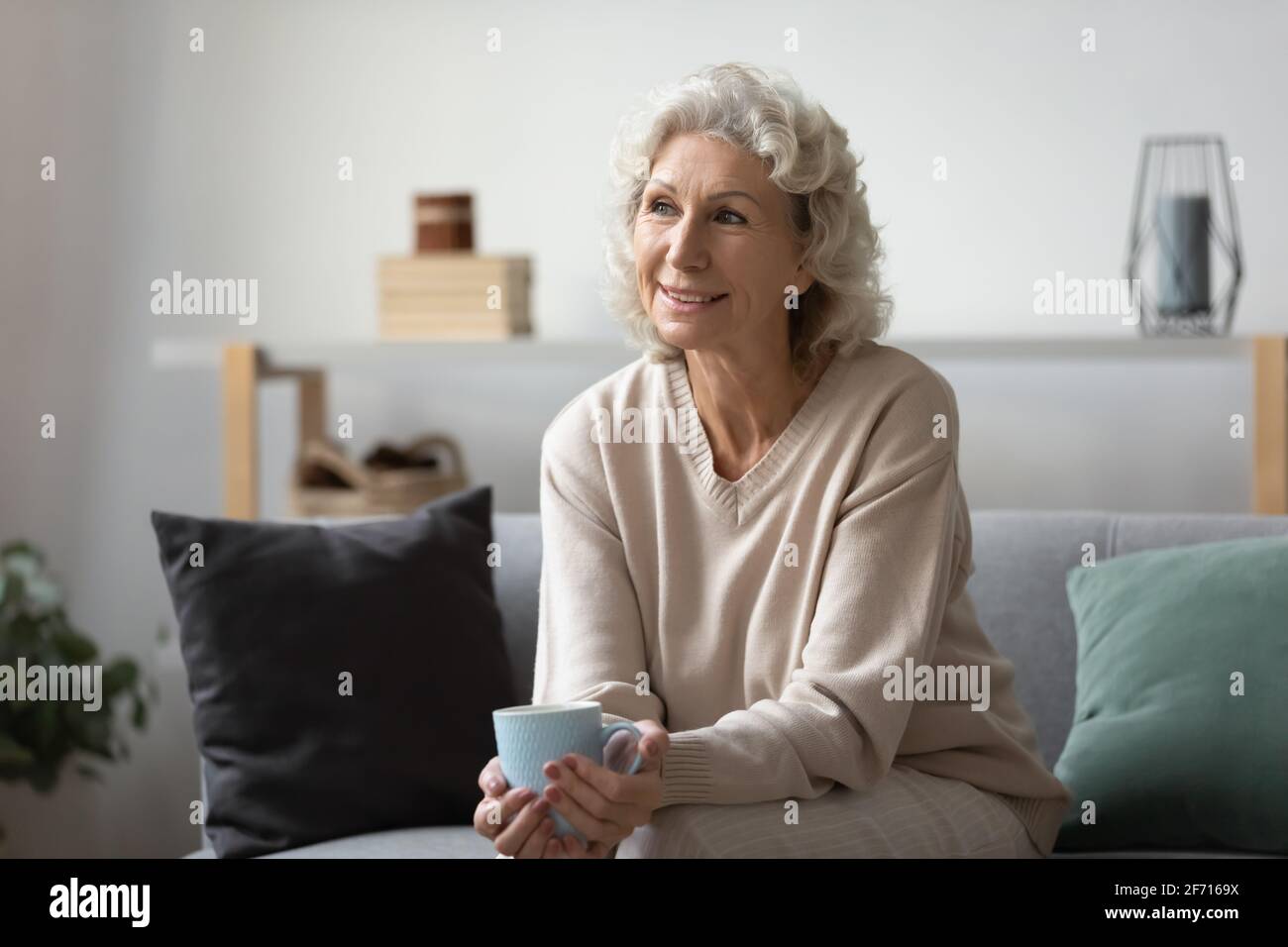 Femme mûre et pensive souriante tenant une tasse de thé ou de café Banque D'Images