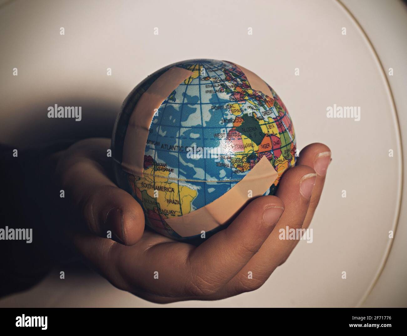 Main d'enfant tenant le globe plein de bandages. Banque D'Images