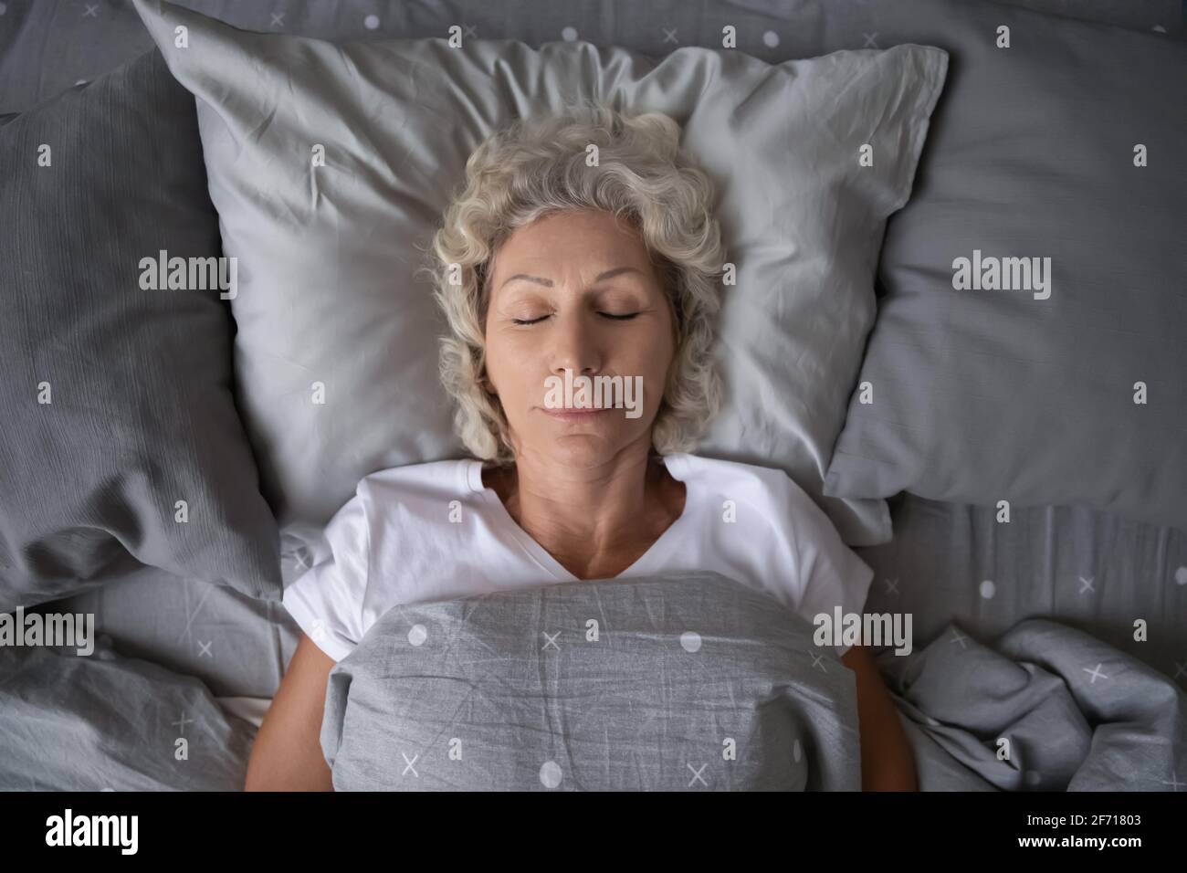 Vue de dessus de la paisible dame d'âge mûr endormie dans la literie Banque D'Images