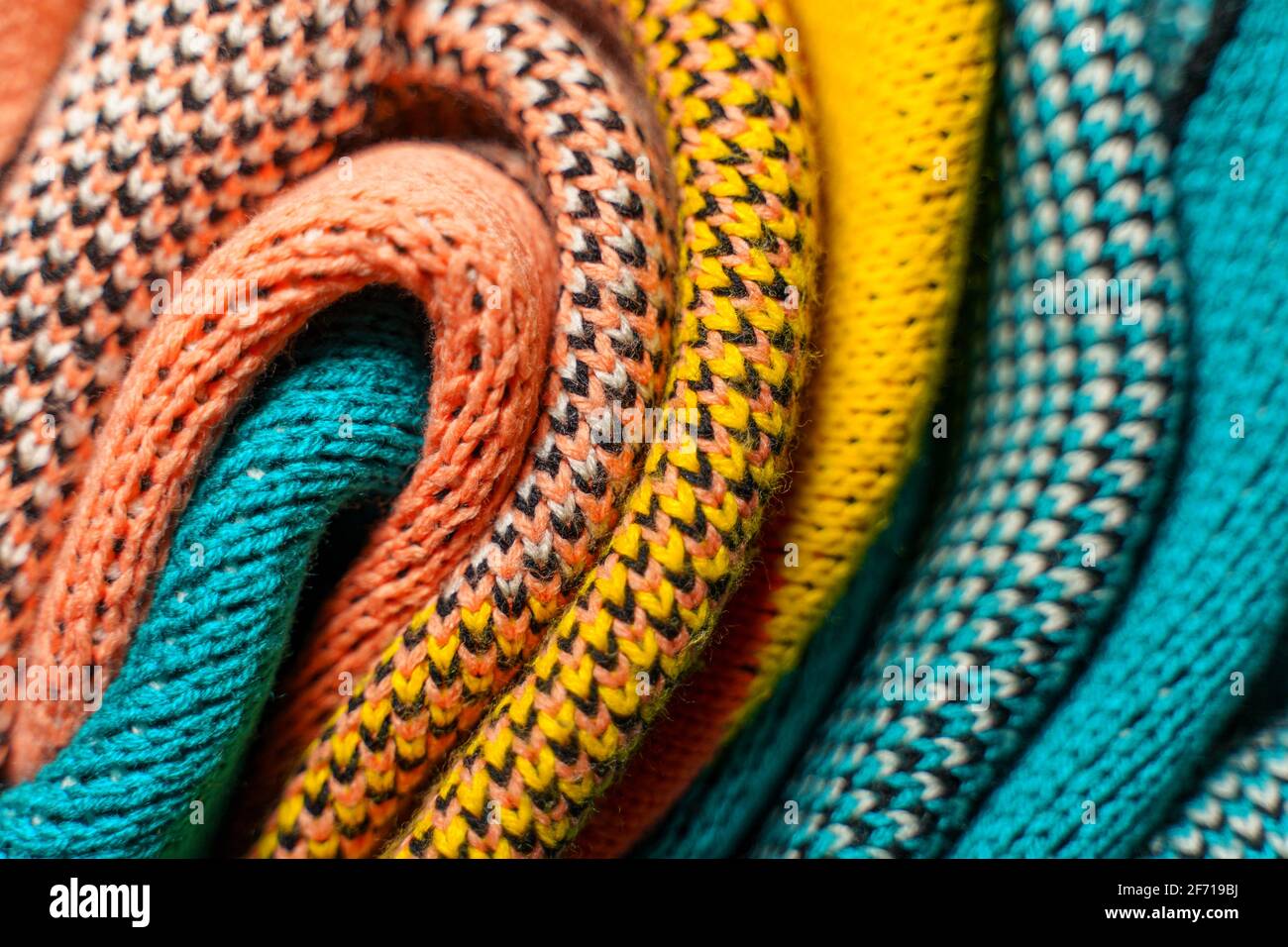 Plis torsadés de tissus tricotés colorés de vêtements d'hiver avec différentes structures et textures. Lisser l'arrière-plan des formes. Multi-colo plié lisse Banque D'Images